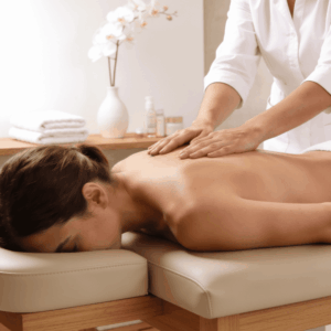 Donna in un centro estetico professionale, sdraiata su un lettino in pelle beige e legno naturale, che riceve da un'estetista in camice bianco un massaggio professionale con la paraffina liquida sulla schiena.