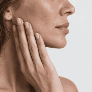 Primo piano laterale di un volto di donna visibile dal naso alla bocca, con una mano poggiata su una guancia